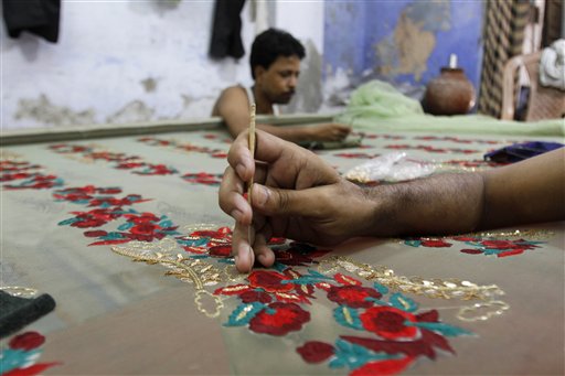 Indian workers embroider a sari at a workshop in New Delhi, India, Wednesday, July 14, 2010. The workers earn Indian Rupees 150 (US$ 3.10) for a 12 hour day of labor. (AP Photo/Rajesh Kumar Singh)