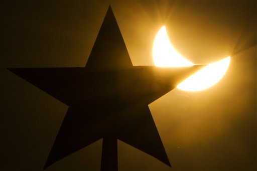 On this photo taken through a solar filter material, the moon blocks part of the sun during a solar eclipse as seen over Moscow Kremlin's Troitskaya (Trinity) tower, in Russia, on Friday, March 20, 2015. An eclipse is darkening parts of Europe on Friday in a rare solar event that won't be repeated for more than a decade.(AP Photo)