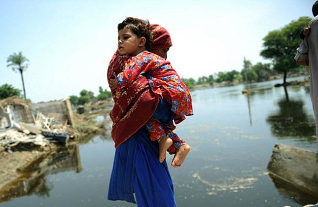 Protective A woman holds her son tight as she crosses a damaged bridge in Kasbag Gujarat