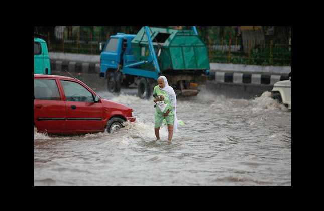 An elderly woman wades through a flooded road during heavy rainfall in Jammu, India, Wednesday, Aug. 25, 2010. Northern India is experiencing heavy rainfall this monsoon season, which usually continues into October. (AP Photo/Channi Anand)