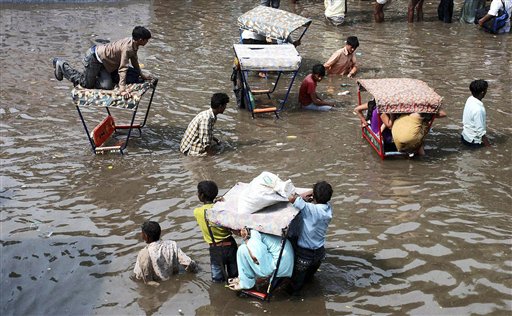 Rickshaw drivers wade waist deep through a flooded road as they carry passengers after heavy rainfall in Mathura, India, Wednesday, Sept. 1, 2010. (AP Photo)