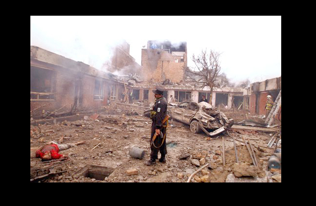 An Afghan police officer looks at the body of an unidentified man lying in the rubble at the scene of an explosion at a guesthouse in Kabul, Afghanistan, Friday, Feb. 26, 2010 (AP Photo/Ahmad Massoud)