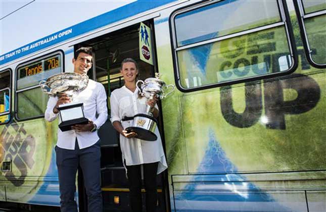 Defending champions Serbia's Novak Djokovic and Victoria Azarenk of Belarus pose with their trophies beside a Melbourne tram prior to the official draw at the Australian Open tennis championship in Melbourne, Australia. (AP Photo)