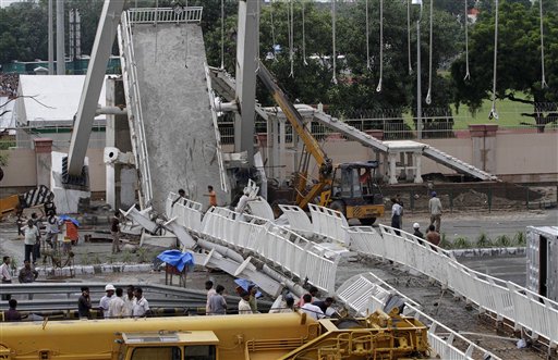 Indian workers stand at the scene of bridge collapse near Jawaharlal Nehru stadium in New Delhi, India, Tuesday, Sept. 21, 2010. A footbridge under construction near the Commonwealth Games main stadium collapsed on Tuesday, injuring people. The games are scheduled to be held from Oct. 3 14. (AP Photo/Anupam Nath)