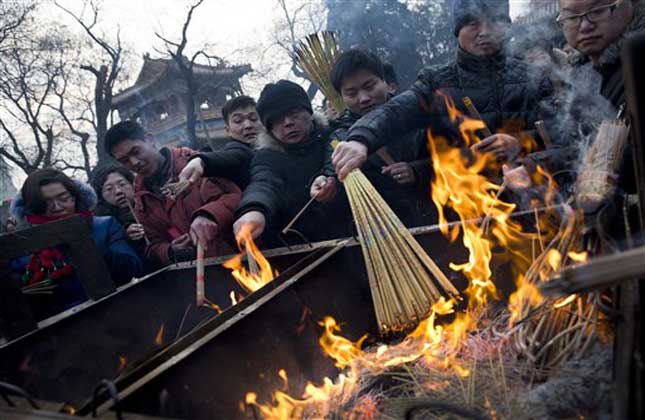 Worshippers burn incense as they pray for health and fortune on the first day of the Chinese Lunar New Year at Yonghegong Lama Temple in Beijing. (AP Photo)