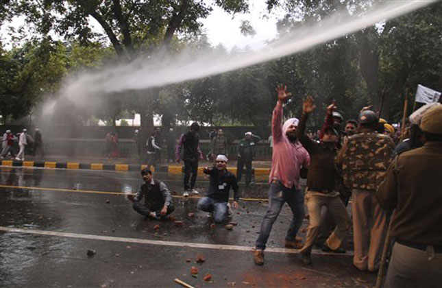 Activist of Aam Aadmi Party, shout slogans as police use water cannons after they clashed with Bharatiya Janata Party (BJP) activists outside the BJP office in New Delhi. (AP Photo)