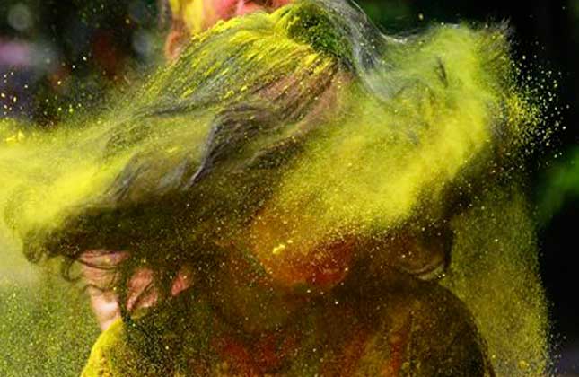 An Indian woman shakes her head covered in colored powder as she celebrates Holi, the Hindu festival of colors, in Mumbai India, Monday, March 17, 2014. The festival heralds the arrival of spring. (AP)