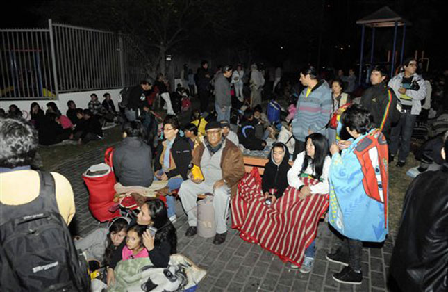 People sit outside as they evacuate their homes after a strong aftershock in Iquique, Chile, early Thursday, April 3, 2014. A powerful aftershock hit Chile's far northern coast late Wednesday night, shaking the same area where a magnitude 8.2 earthquake hit just a day before causing some damage and six deaths. (AP Photo)