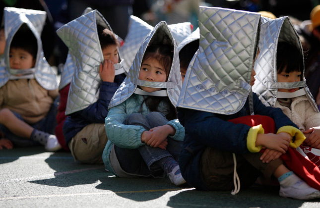 Kindergarten students sit in a playground during an earthquake simulation exercise at an elementary school in Tokyo.