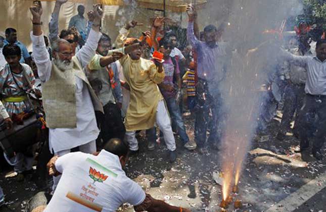 Bharatiya Janata Party (BJP) supporters set off firecrackers and dance to celebrate preliminary results that showed the BJP winning by a landslide, outside the party headquarters in New Delhi, India, Friday, May 16, 2014. India's opposition leader Narendra Modi and his party won national elections in a landslide Friday, preliminary results showed, driving the long dominant Congress party out of power in the most commanding victory India has seen in more than a quarter century. (AP Photo)