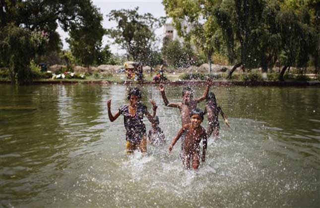 Indian children play in a pond on a hot summer afternoon in New Delhi, India, Friday, June 6, 2014. Heat wave conditions prevailed in the capital with mercury crossing 46.7 degrees Celsius