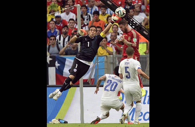 Chile's goalkeeper Claudio Bravo, left, clears the ball from Spain's Sergio Ramos during the group B World Cup soccer match between Spain and Chile at the Maracana Stadium in Rio de Janeiro, Brazil, Wednesday, June 18, 2014. (AP Photo)