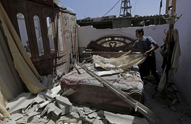 A Palestinian relative of neighbors of a house belonging to the Abu Hamada family, inspects the damage to a bedroom in their house, after an Israeli strike in Jebaliya refugee camp, in the northern Gaza Strip, Monday, Aug. 25, 2014. (AP Photo)