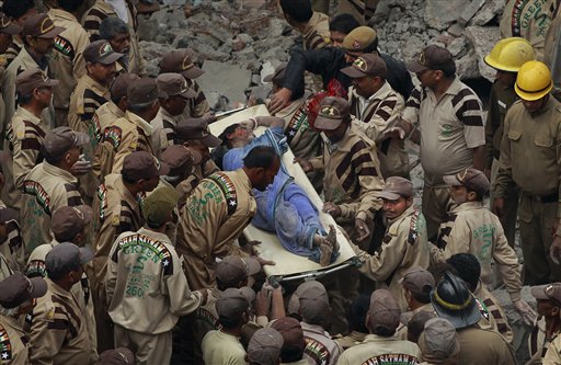 Rescue workers carry the body of a woman from the remains of a four story apartment building that collapsed into a mountain of concrete in New Delhi, India, Tuesday, Nov.16, 2010. Dozens were killed and scores of others injured.(AP Photo/Kevin Frayer)