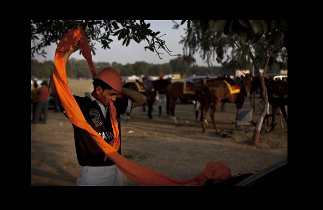 A rider from the Indian Army's 61st Cavalry wraps a turban on his head at the Cavalry Gold Cup Polo match at the Jaipur Polo Grounds in New Delhi, India, Sunday, Dec. 12, 2010. (AP Photo/Kevin Frayer)