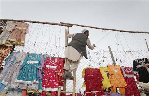 An Afghan seller of traditional clothes makes place to hang the clothes for sale in Kabul, Afghanistan on Tuesday, March 2, 2010. (AP Photo/Musadeq Sadeq)