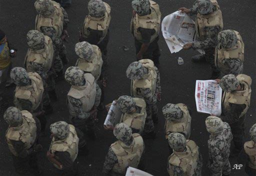 Egyptian army soldeirs read newspapers as they wait for Friday prayers followed by a demonstration in Tahrir square, Cairo, Egypt, Friday Feb. 18, 2011. Protests continued and labor unrest has increased in Egypt since President Hosni Mubarak's departure last week that set off a chain reaction around the Middle East, with anti government demonstrations reported in Libya, Bahrain and Yemen.(AP Photo/Enric Marti)