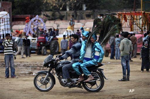 An Indian man carries artists on his motorbike as another takes a photograph with his mobile phone during a procession on the eve of Shivratri festival, in Jammu, India, Tuesday, March 1, 2011. Shivratri, a festival dedicated to the worship of Hindu God Shiva, will be marked across the country Wednesday. (AP Photo/Channi Anand)