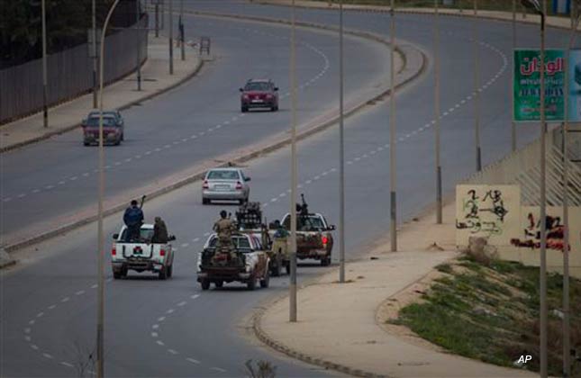 Libyan rebels drive through the deserted city of Benghazi after a plane of Gadhafi's forces was shot down over , eastern Libya, Saturday, March 19, 2011. Explosions shook the Libyan city of Benghazi early on Saturday while a fighter jet was heard flying overhead, and residents said the eastern rebel stronghold was under attack from Muammar Gaddafi's forces. (AP Photo/Anja Niedringhaus)