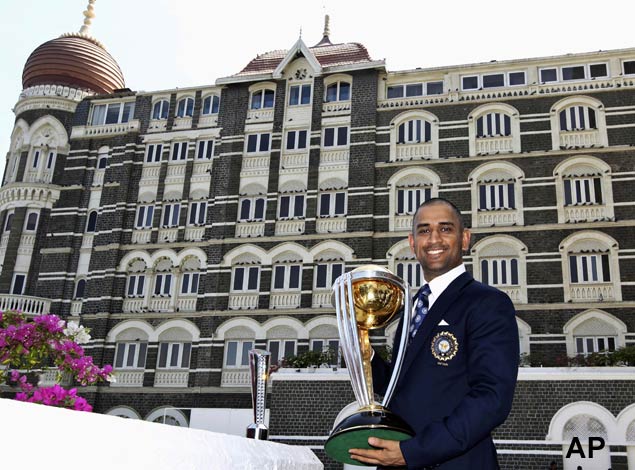 Indian captain Mahendra Singh Dhoni poses with the trophy in the backdrop of the Taj Mahal hotel in Mumbai, India, Sunday, April 3, 2011. Dhoni lofted Sri Lanka's Nuwan Kulasekara for the winning six against Sri Lanka, leading India to the six wicket victory at the Wankhede Stadium, when Dhoni anchored the run chase with his knock of 91. India won the Cricket World Cup for the first time in 28 years. (AP Photo/Gurinder Osan)