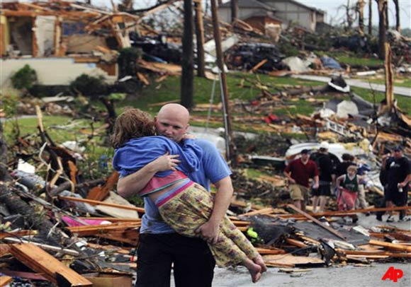 A man carries a young girl who was rescued after being trapped with her mother in their home after a tornado hit Joplin, Mo. on Sunday evening, May 22, 2011. The tornado tore a path a mile wide and four miles long destroying homes and businesses. (AP Photo/Mike Gullett)