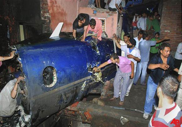 Indian residents search around the wreckage of a small plane after it crashed into a residential community in Faridabad, near New Delhi, India, late Wednesday, May 25, 2011. A government official says the crash of a small chartered plane in a residential area on the outskirts of the Indian capital has killed at least 10 people and injured another two. (AP Photo)