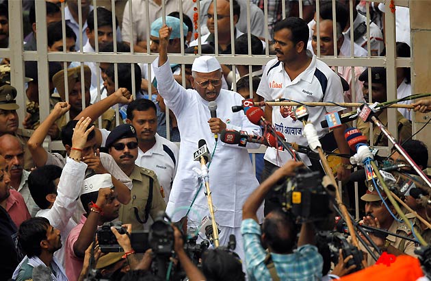 India's most prominent anti corruption crusader Anna Hazare, center, raises slogans after emerging from the gates of Tihar prison where he was lodged since Aug. 16, in New Delhi, India, Friday, Aug. 19, 2011. Nearly 2,000 men, women and schoolchildren had gathered outside the jail on Friday morning to catch sight of the white clad activist who has channeled the tactics of freedom fighter Mohandas K. Gandhi into his fight to force the government to adopt his proposals for an anti corruption law. (AP Photo/Saurabh Das)