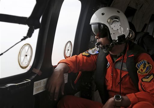 A crew member of Indonesian Air Force NAS 332 Super Puma helicopter, looks out of the windows during a search operation for the victims and wreckage of AirAsia Flight QZ 8501 over the Java Sea, Indonesia