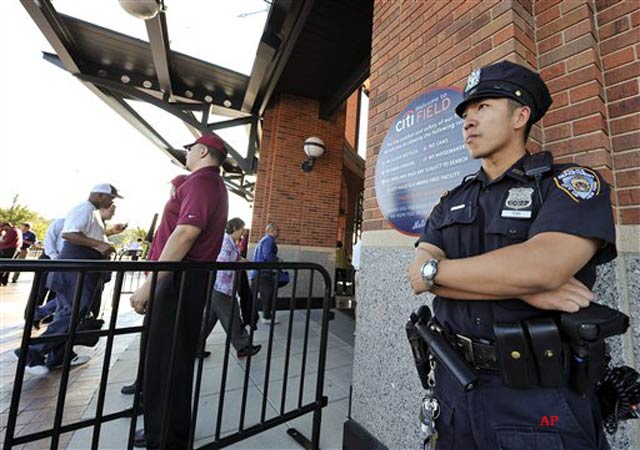 New York City Police officer King Tung, right, stands outside the rotunda entrance to Citi Field as fans enter the stadium before a baseball game between the New York Mets and the Chicago Cubs, Friday, Sept. 9, 2011, in New York. The latest threat, potentially targeting New York or Washington, prompted an even greater security surge in those cities. Law enforcement around the country had already increased security measures at airports, nuclear plants, train stations and more in the weeks leading up to the 10th anniversary of the Sept. 11 attacks. (AP Photo/Kathy Kmonicek)