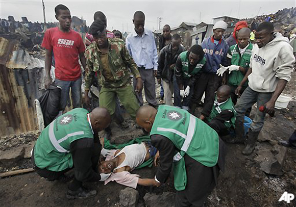 Joseph Mwangi, 34, is aided by ambulance workers as he lies in a state of shock after discovering the charred remains of two of his children, one aged 6 the other of unknown age, at the scene of a fuel explosion in Nairobi, Kenya, Monday, Sept. 12, 2011. A leaking gasoline pipeline in Kenya's capital exploded on Monday, turning part of a slum into an inferno in which at least 75 people were killed and more than 100 hurt.(AP Photo/Ben Curtis)