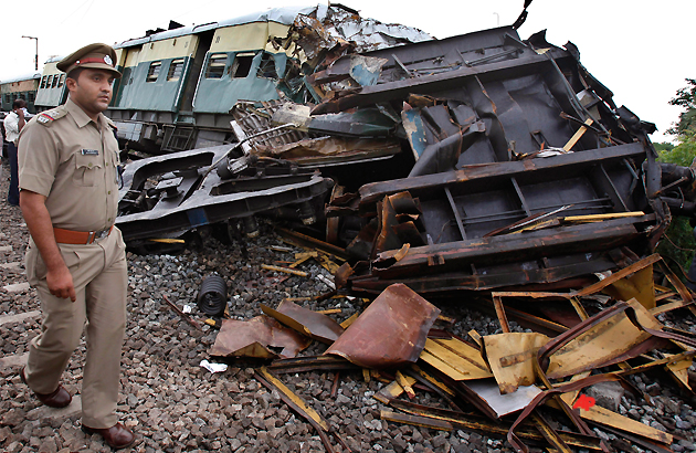 A police officer walks past wreckage of derailed compartments after two trains collided near Arakkonam, southwest of Chennai, India, Wednesday, Sept. 14, 2011. A passenger train traveling through southern India collided with another train stopped at a signal on Tuesday, killing ten people and injuring dozens more, a government official said. (AP Photo/Aijaz Rahi)