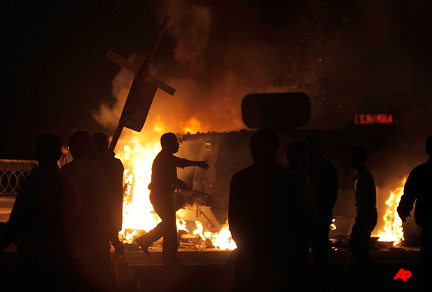 Coptic Egyptian demonstrators, one carrying a wooden Christian cross, set on fire an army vehicle during cashes with Egyptian Army soldiers following a demonstration in Cairo, Egypt Sunday, Oct. 9, 2011. Egyptian state television reports at least one soldier has been killed in riots that erupted in Cairo as Christians protesting a recent attack on a church came under attack. (AP Photo/Nasser Nasser)