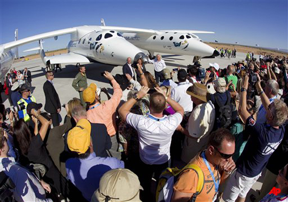 Guests try to photograph British Billionaire Richard Branson, standing in front of SpaceShipTwo, center, and WhiteKnightTwo, outside the new Spaceport America hangar Monday, Oct. 17, 2011 in Upham, NM. Branson was dedicating the newly completed terminal and hangar where his Virgin Galactic will stage its commercial space tourism venture. (AP Photo/Matt York)