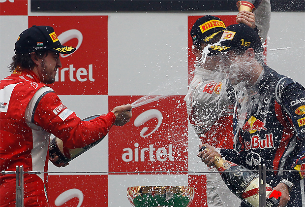 Winner Red Bull driver Sebastian Vettel of Germany, right, is poured champagne on by Ferrari driver Fernando Alonso of Spain, left, third place, on the podium of the Indian Formula One Grand Prix at the Buddh International Circuit in Noida, 38 kilometers (24 miles) from New Delhi, India, Sunday, Oct. 30, 2011. (AP Photo/Gurinder Osan)