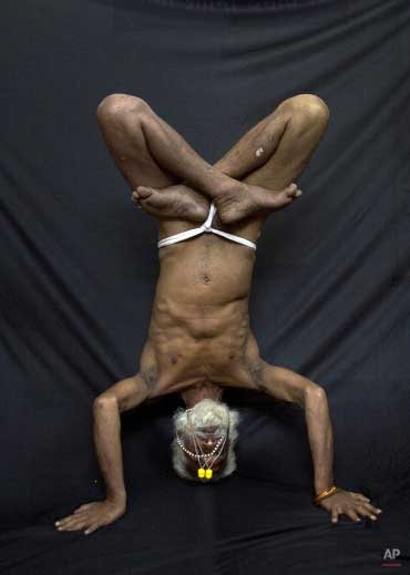 Bhrahaspati Bharti Baba, an Indian Hindu holy man, demonstrates the yoga pose Baddha Padmasana, or Locked Lotus pose, where the arms are twisted around the back, in Gauhati.