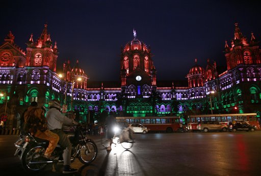 Commuters move past the Chhatrapati Shivaji train station building illuminated with the three colors of the Indian flag on Republic Day in Mumbai