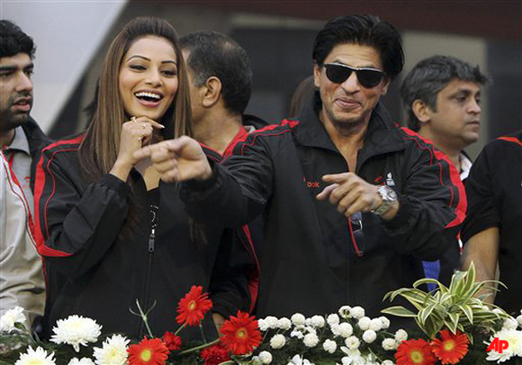 Bollywood actors Shah Rukh Khan , right, and Bipasha Basu laugh as they make an appearance at the start/finish area of the Airtel Delhi Half Marathon in New Delhi, India, Sunday, Nov. 27, 2011. Lelisa Desisa of Ethiopia won the men's race in 59 30 and Lucy Kabuu of Kenya won the women's race in 1 07 04. (AP Photo)