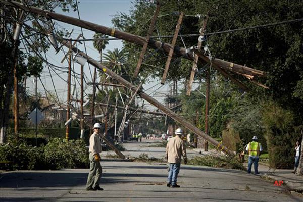 Crews from Southern California Edison power company work to clean up and restore power on Live Oak Avenue, Friday, Dec. 2, 2011, in Temple City, Calif. With more than 100,000 people still without power Friday from one of the biggest windstorms to hit the Western United States in years, people began cutting up felled trees, hauling away trash and firing up power generators. Particularly hard hit was the Los Angeles suburb of Temple City, where winds toppled telephone poles like dominos, leaving three quarters of the city's 35,000 residents without power for several days. (AP Photo/Bret Hartman)