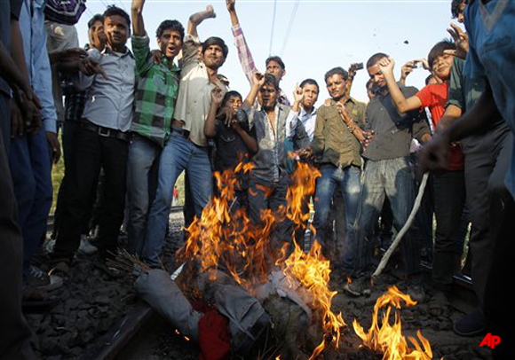 Indian protestors burn an effigy of a state lawmaker on a railway track in Bhopal, India, Saturday, Dec 3, 2011. Thousands of survivors of the world's worst industrial accident blocked trains through a central Indian city on Saturday to demand more compensation. The protests were on the 27th anniversary of the disaster in Bhopal, where a Union Carbide pesticide plant leaked lethal gas that killed an estimated 15,000 people and maimed tens of thousands more. (AP Photo/Rafiq Maqbool)