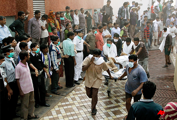 People help carry a patient out of a hospital after it caught fire in Kolkata, India, Friday, Dec. 9, 2011. The fire swept through the hospital early Friday, sending emergency workers scrambling to evacuate patients and medical staff from the smoke filled building, officials said. (AP Photo/Bikas Das)