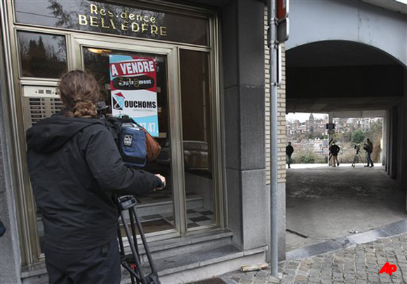 A cameraman films the entrance of the appartment block of a grenade lobbing gunman, in Liege, Belgium, Wednesday, Dec. 14, 2011. The body of a woman has been found in the garage of a grenade lobbing gunman who killed three people and injured 123 others in an attack in the city of Liege, officials said Wednesday. (AP Photo/Yves Logghe)