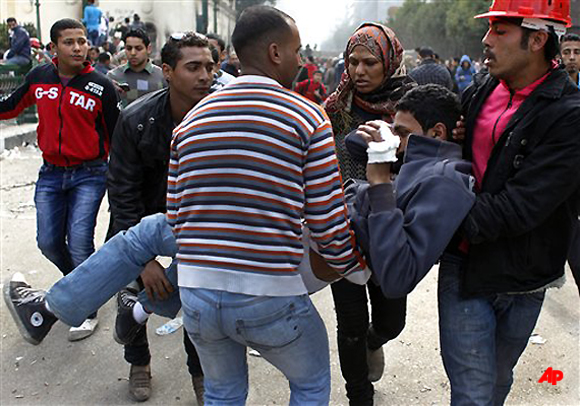 Egyptian protesters evacuate an injured fellow protester during clashes with army soldiers near Tahrir Square in Cairo, Sunday, Dec. 18, 2011. Egypt's military sought to isolate pro democracy activists protesting against their rule, depicting them as conspirators and vandals, as troops and protesters clashed for a third straight day, pelting each other with stones near parliament in the heart of the capital. (AP Photo/Nasser Nasser)