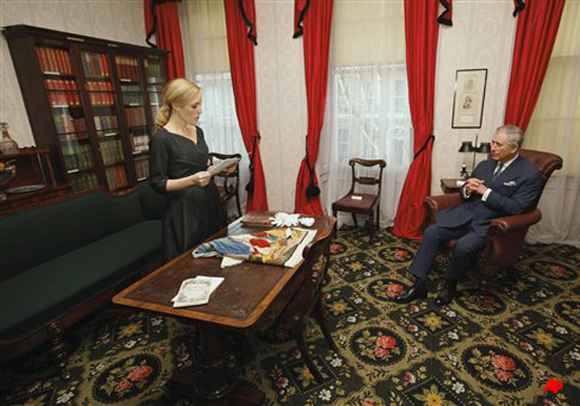 Actress Gillian Anderson reads a Charles Dickens book to Britain's Prince Charles, right, during his visit to the Dickens Museum in London Tuesday Feb. 7, 2012. Prince Charles led ceremonies Tuesday to mark the 200th birthday of novelist Charles Dickens a writer as popular today as he was during his lifetime. (AP Photo/Andrew Winning, Pool)