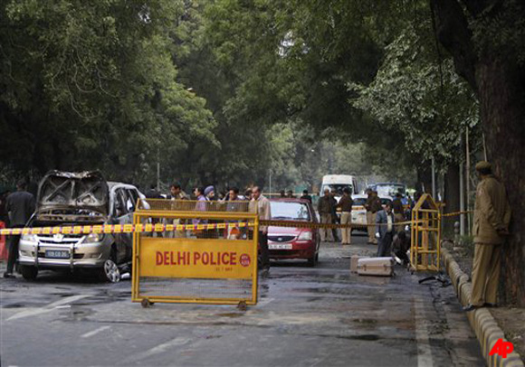 Indian security and forensic officials examine a car belonging to the Israel Embassy, left, after an explosion tore through that in New Delhi, India, Monday, Feb. 13, 2012. The driver and a diplomat's wife were injured, according to Indian officials. (AP Photo/Mustafa Quraishi)