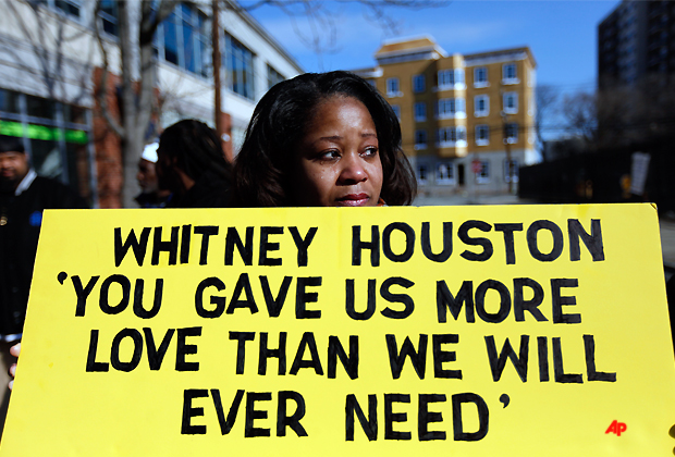 Renee Taylor, of Baltimore, Md., stands with a sign a few blocks from the New Hope Baptist Church before the funeral of Whitney Houston in Newark, N.J., Saturday, Feb. 18, 2012. (AP Photo/Jason DeCrow)