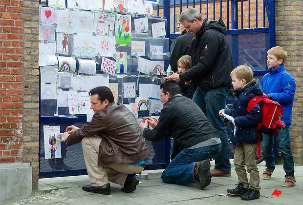 Teachers of the Sint Lambertusschool in Heverlee, Belgium, attach drawings of pupils at the gate of the school, Wednesday March 14, 2012. A tour bus slammed into a tunnel wall in the Swiss Alps on Wednesday morning in a horrific accident that killed 22 Belgian 12 year old students returning from a joyous ski vacation as well as the six adults who were accompanying them, police said Wednesday. Children from the school were involved in the bus crash in Switzerland. (AP Photo/Geert Vanden Wijngaert)