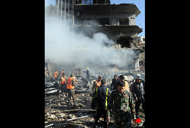 In this photo released by the Syrian official news agency SANA, Syrian army soldiers and security officers inspect the blast area in front of a damaged building of the air intelligence forces, which was attacked by one of two explosions, in Damascus, Syria, on Saturday, March 17, 2012. Two terrorist explosions struck security targets in the Syrian capital Saturday morning, killing a number of civilians and security forces, the country's state news agency said. The report said preliminary reports indicated they blasts were caused by car bombs that hit the aviation intelligence department and the criminal security department. (AP Photo/SANA)