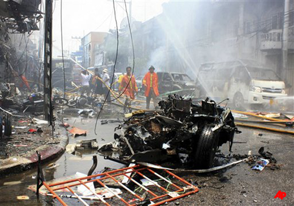 Thai fire fighters walk near a wreckage of a car while others trying to put off fire at a building after the car bomb blasted in Yala, southern Thailand, Saturday, March 31, 2012. Suspected Muslim insurgents set off coordinated bomb blasts as shoppers gathered for lunch Saturday in a busy hub of Thailand's restive south, killing eight people and wounding more than 60, officials said. (AP Photo)