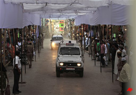 Indian Muslims watch policemen perform a security drill on a road leading to Ajmer Sharif, the shrine of Sufi saint Khwaja Moinuddin Chishti, where Pakistani president Asif Ali Zardari will visit Sunday, in Ajmer, in India's western state of Rajasthan, Saturday, April 7, 2012. Zardari's trip to New Delhi, the first by a Pakistani head of state since 2005, is the most visible sign that the rivals have put the enmity that followed the 2008 terror attacks in the Indian city of Mumbai behind them and are working to strengthen economic and political ties. (AP Photo/Manish Swarup)