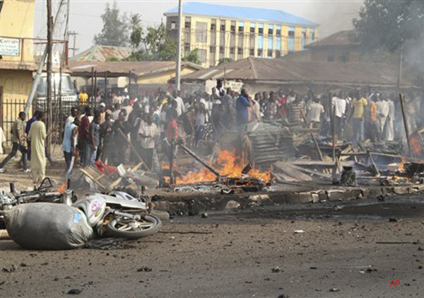 People gather at the site of a bomb explosion at a road in Kaduna, Nigeria on Sunday, April 8, 2012. An explosion Kaduna in central Nigeria that has seen hundreds killed in religious and ethnic violence in recent years, causing unknown injuries as diplomats had warned of possible terrorist attacks over the Easter holiday, police said.(AP Photos/Emma Kayode)